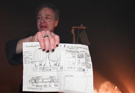 Die Dragqueen zeigt einen Plan. Darauf hat sie gezeichnet, wie ein Luftschiff funktionieren kann.