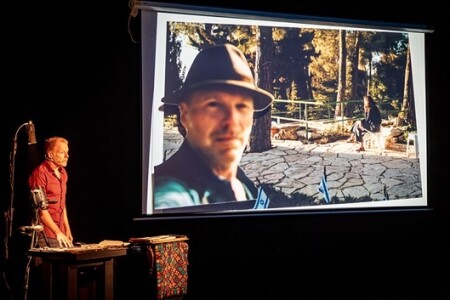 Volker Gerling auf der Bühne. An der Wand ist ein Foto von ihm projiziert.